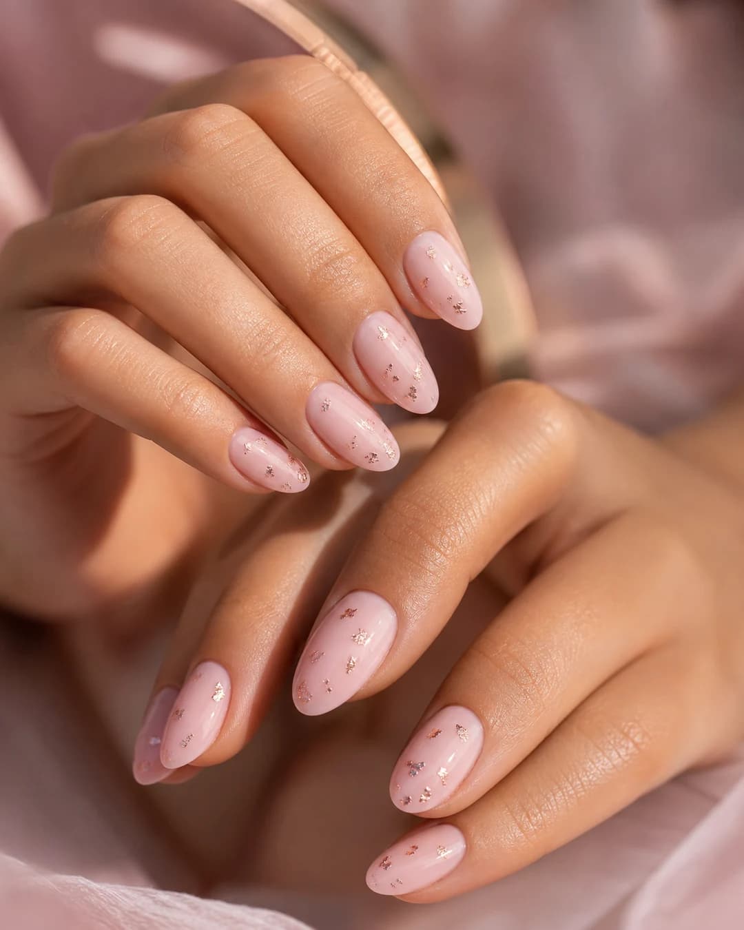 Uñas almendradas con base rosa palo y foil rose gold delicado distribuido sutil estilo coquette
