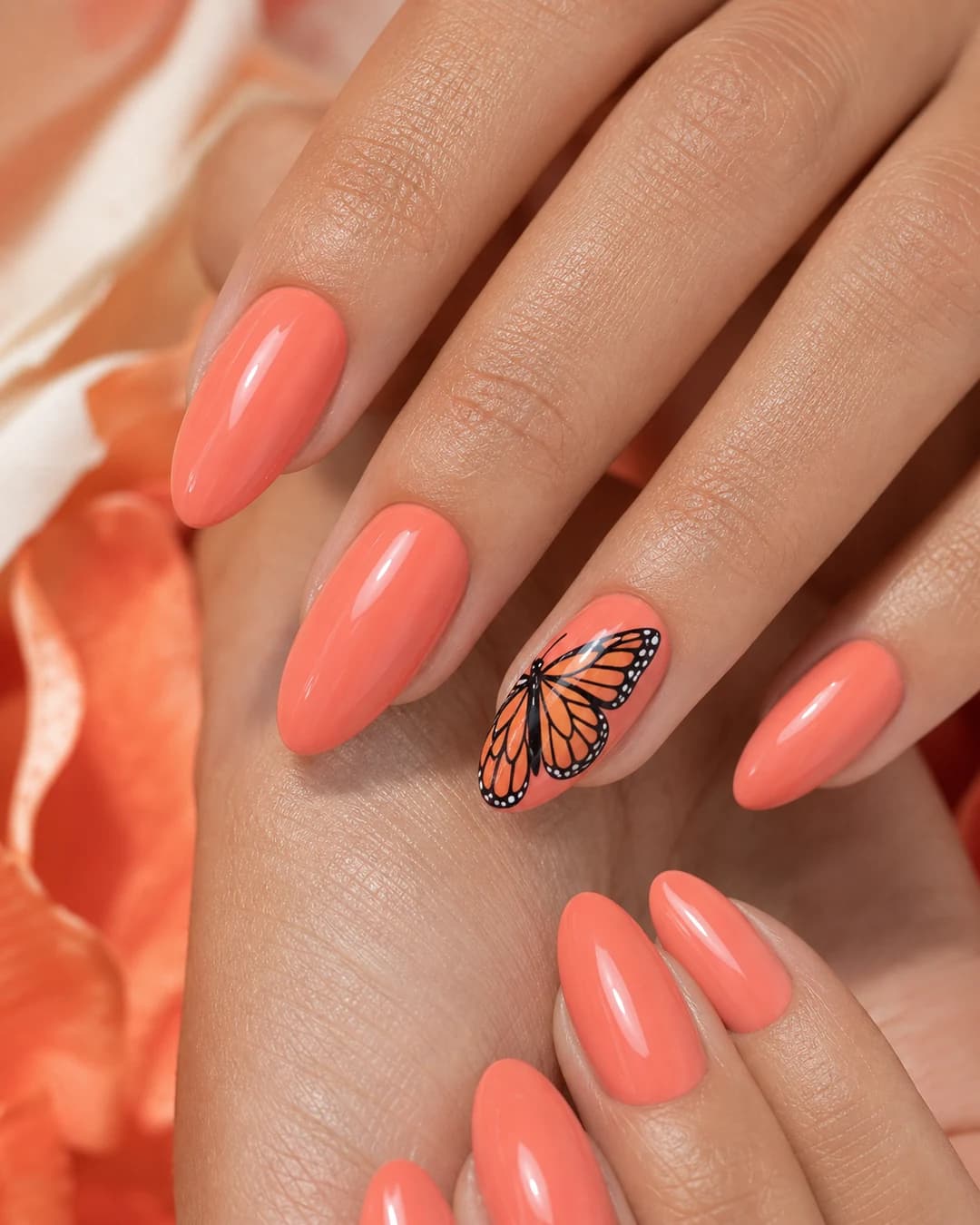 Uñas coral con una mariposa monarca naranja-negra pintada en el anular
