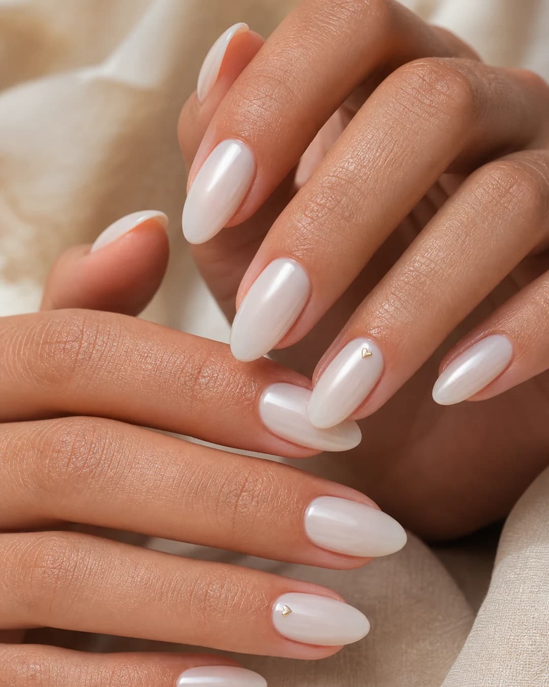 Uñas lechosas con un micro corazón dorado pintado en la lúnula del anular